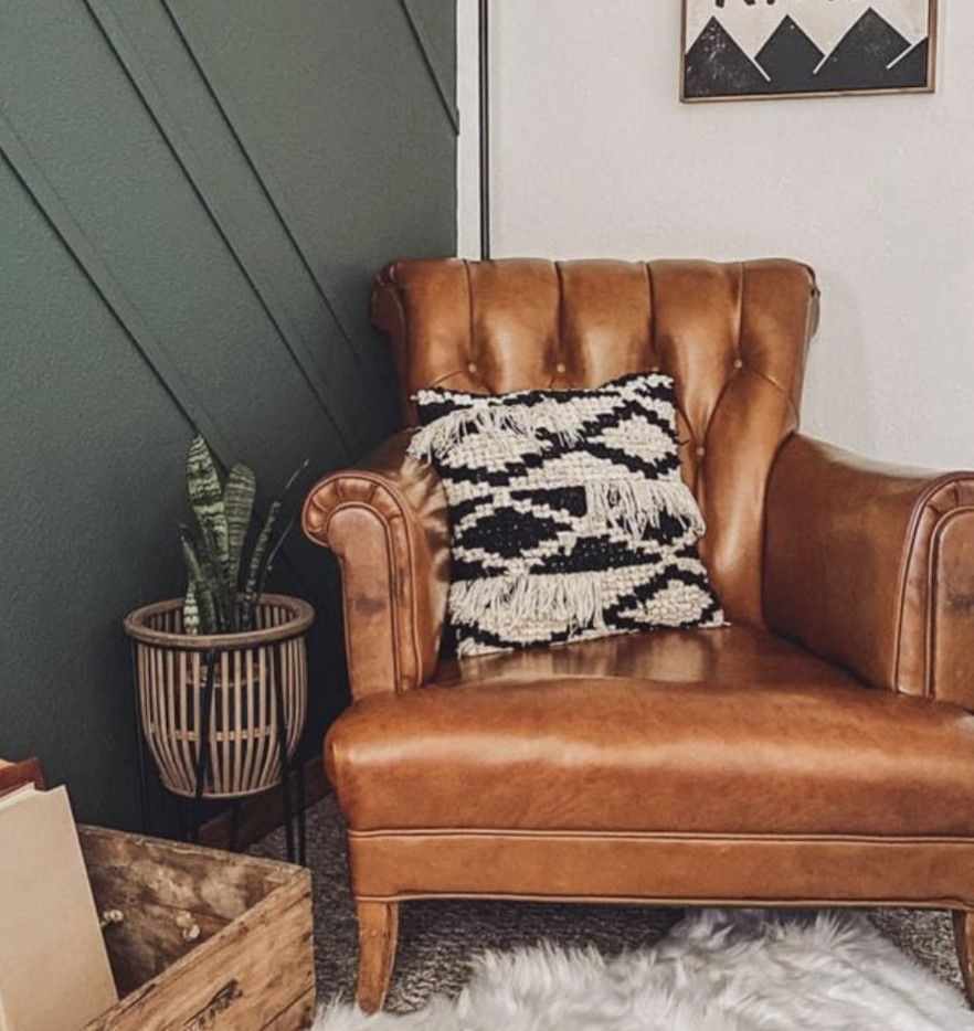 A brown leather chair in olive green bedroom and fur rug on the floor