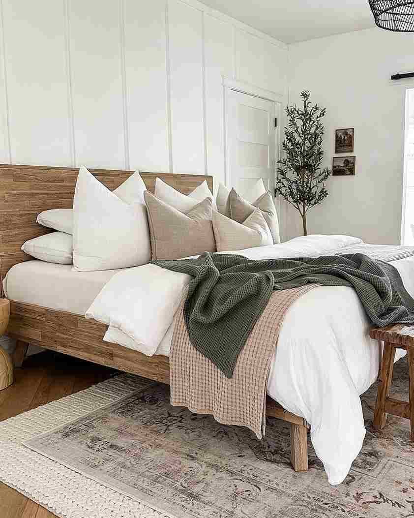 A white bedroom with wooden bed and pillow and rug