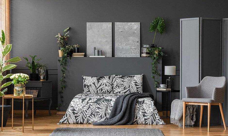 A grey bedroom with plants in the bedroom and a chair and wooden floor and grey rug on it