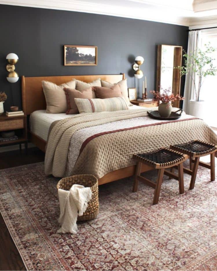 A black wall with tan accents and gold frame painting and lights on wall