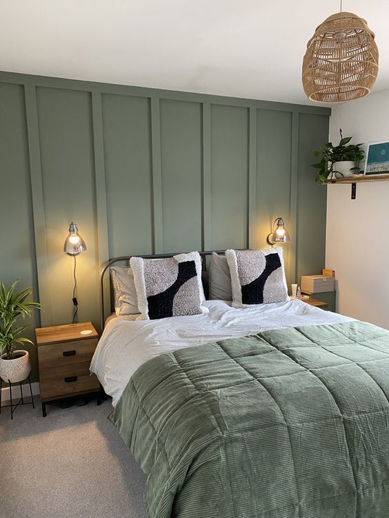 A board-and-batten sage green wall with bed and lights on the wall