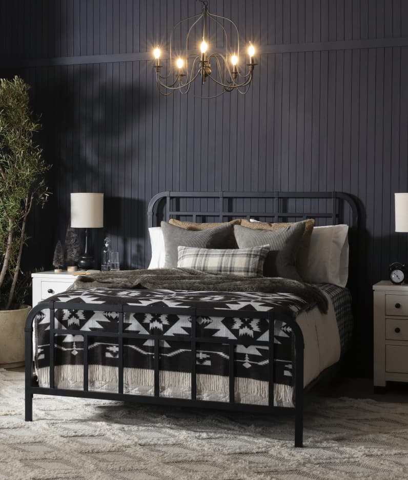 A black bedroom with black framed bed and side table