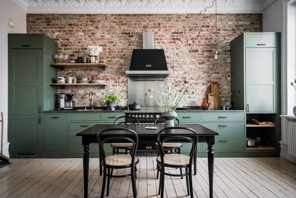 A sage green with wooden black table and chairs and brick wall