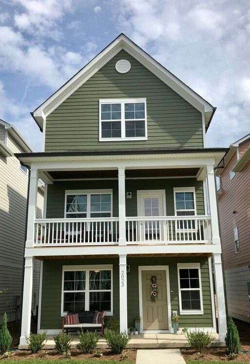 A green house with white windows and balcony 