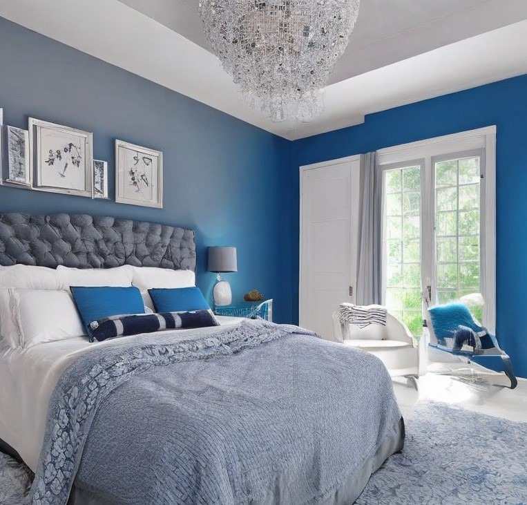 A blue and light blue bedroom with white bed and wooden floor and framed on the wall
