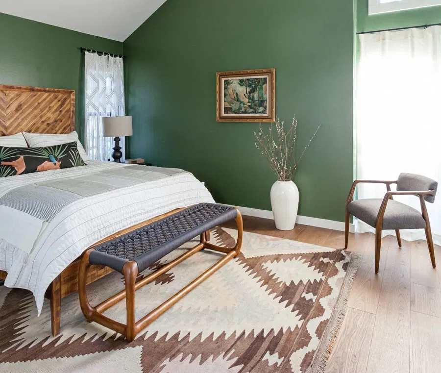 A green bedroom with grey accents and brown rug 