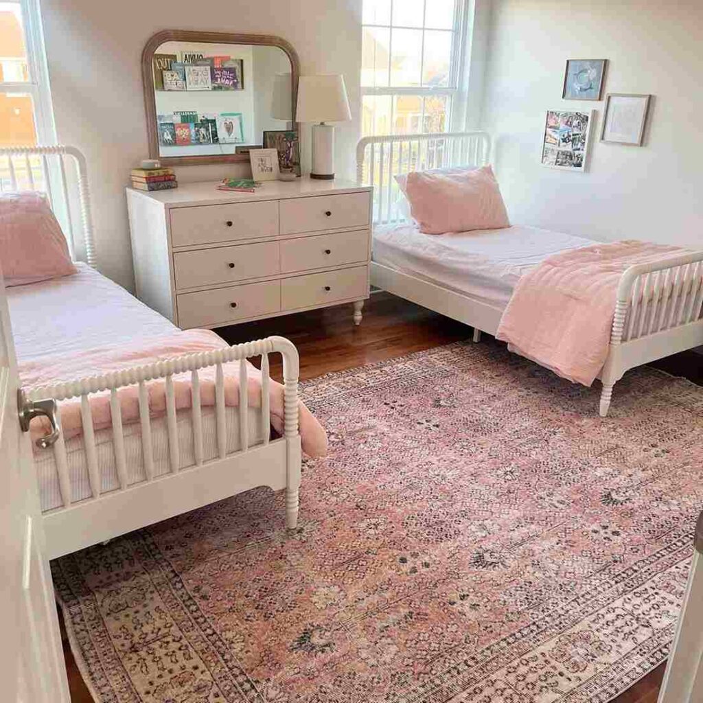 A bedroom with rug under the both bed and dresser in the middle of bed 