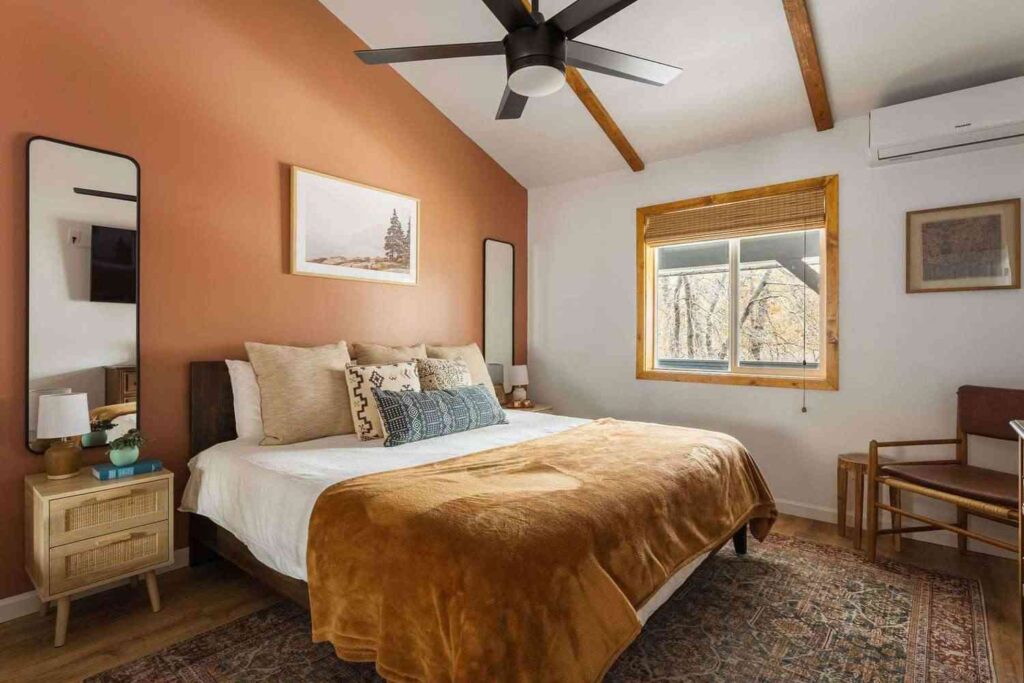 A bedroom with earthy palette with white trim and mirror on the wall