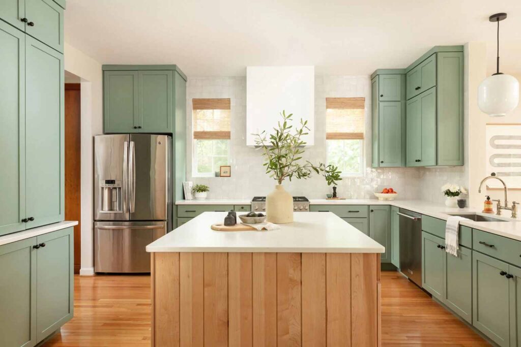A sage green cabinets in kitchen and wooden accents and woden floor