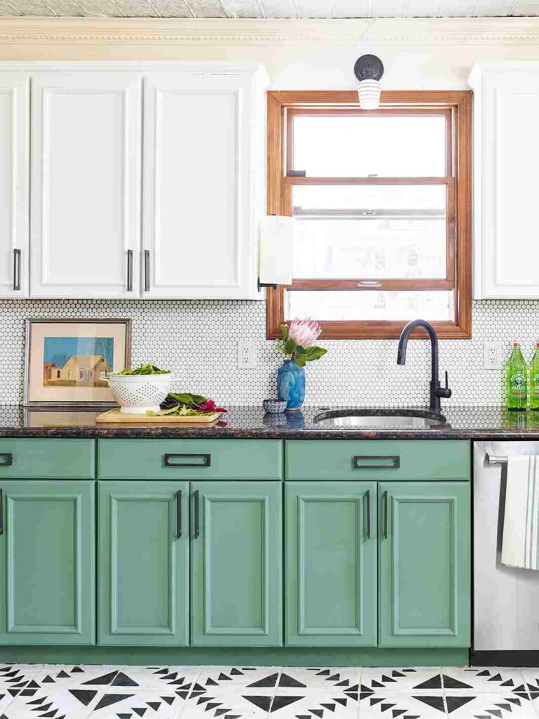 A sage green cabinets and white countertop and wooden framed windows
