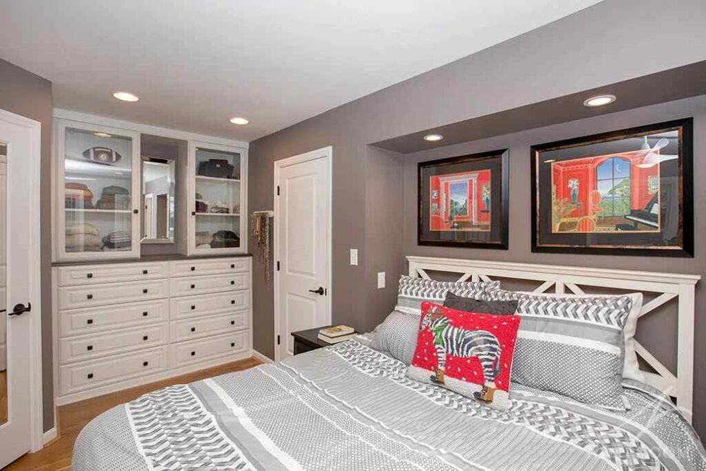 A bedroom with built-ins and black framed painting on the wall