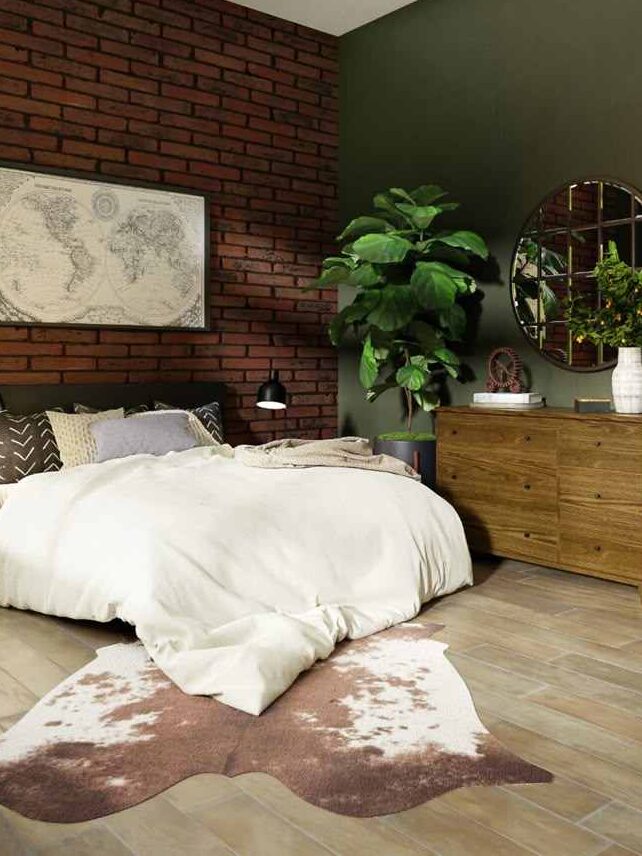 A green bedroom with brick accents and wooden deck and bd with pillows and blankets 