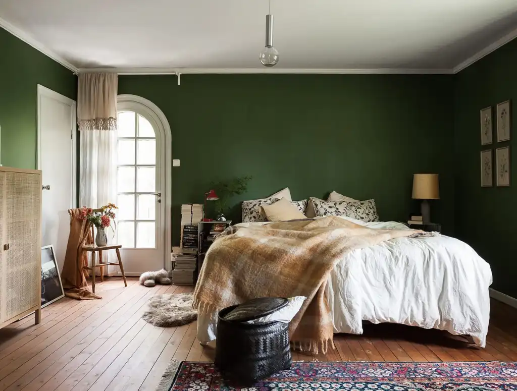 A olive green bedroom with white celling and wooden floor
