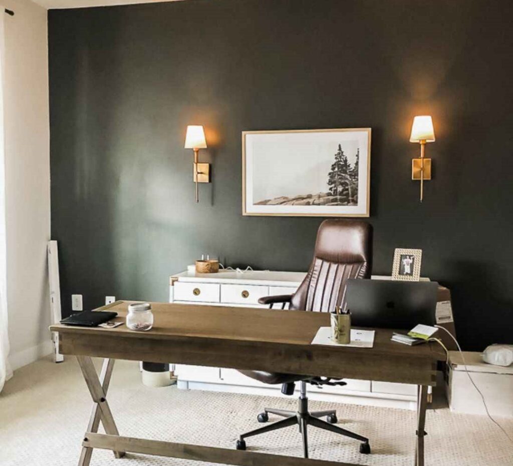 Green wall with golden and white wall sconce and a wooden table