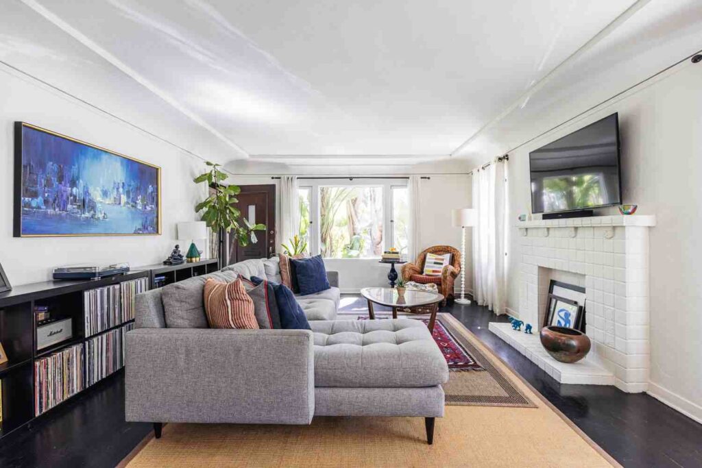 A small living room with wooden floor and tv on the wall
