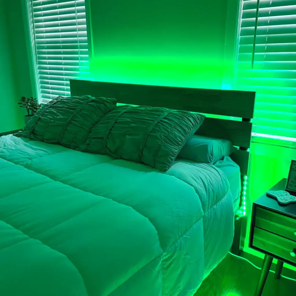 A green bedroom with windows and lights behind the bed 