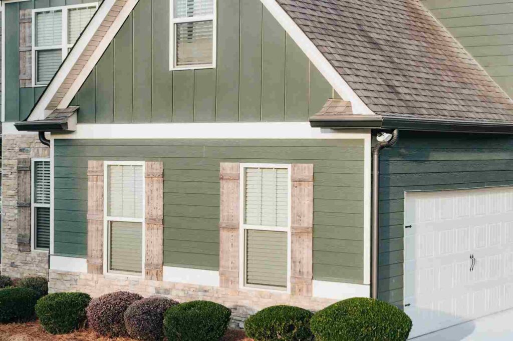 Light green home with black gutter and white trim and wooden shutters