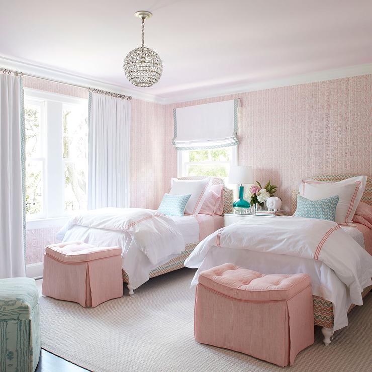 twin beds with pink accents with pink ottomans and white windows 