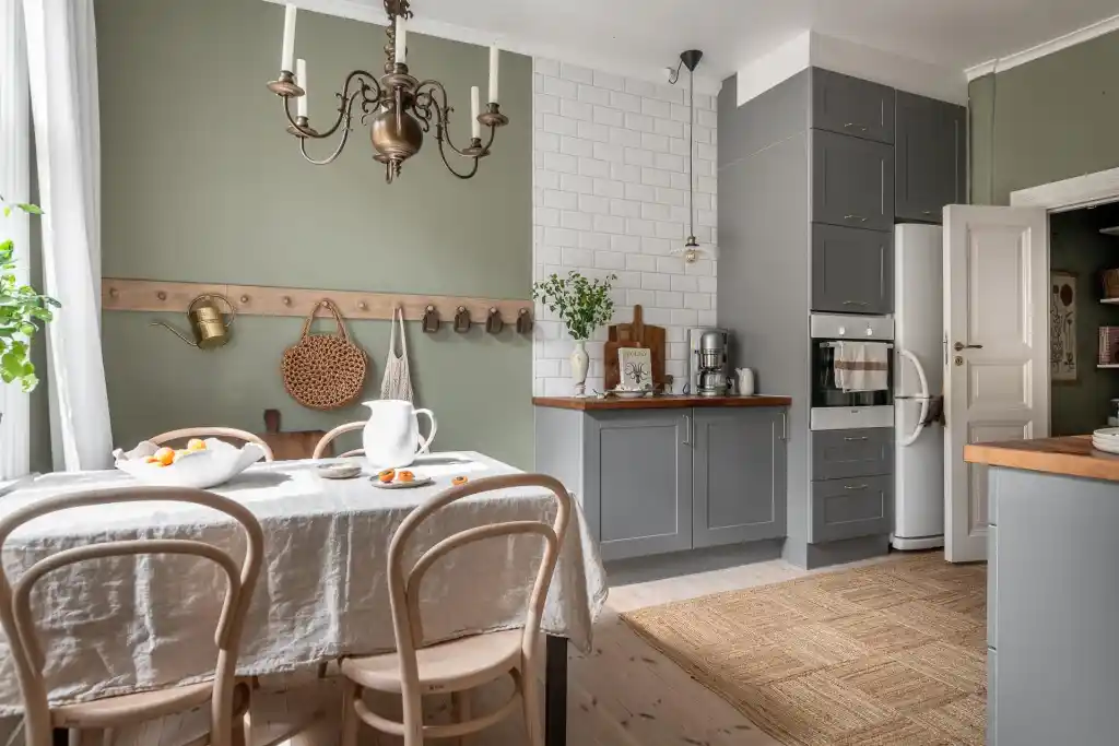A sage green wall and grey cabinets and white door and wooden floor
