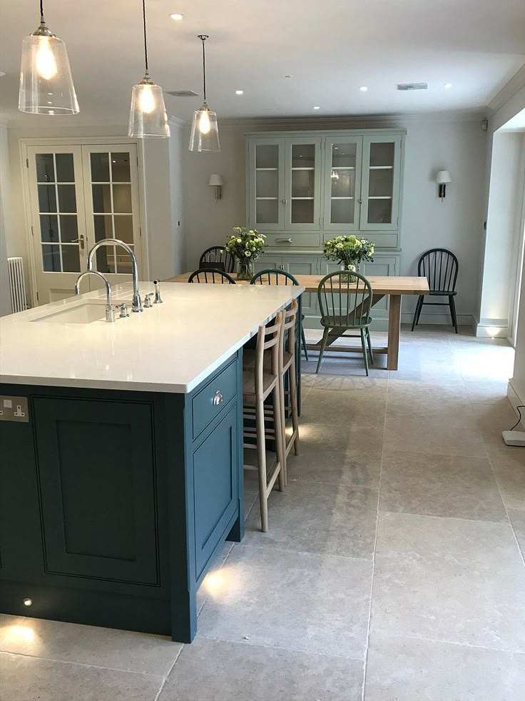 A kitchen with navy blue island and sage green island and white counter top