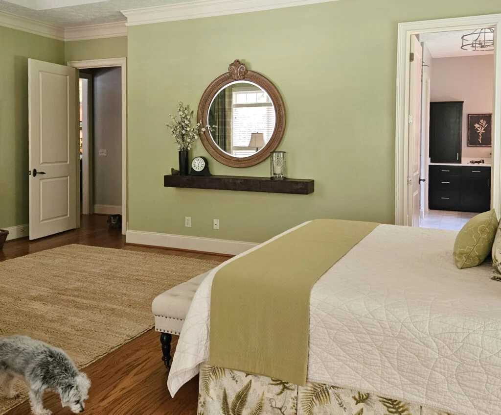 A green wall with cream trim and mirror on the wall