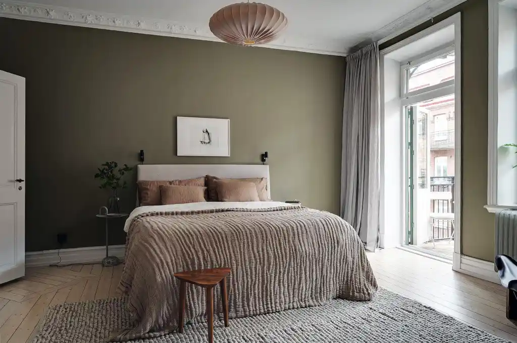 A olive bedroom with bed and rug on the floor