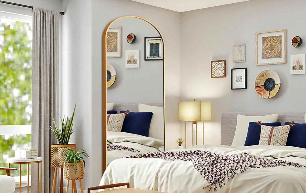 A bedroom with full length mirror in the bedroom and brass plants