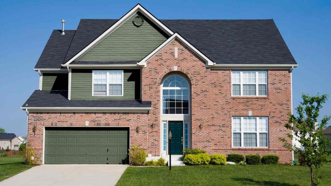Red brick house with green siding and black roof