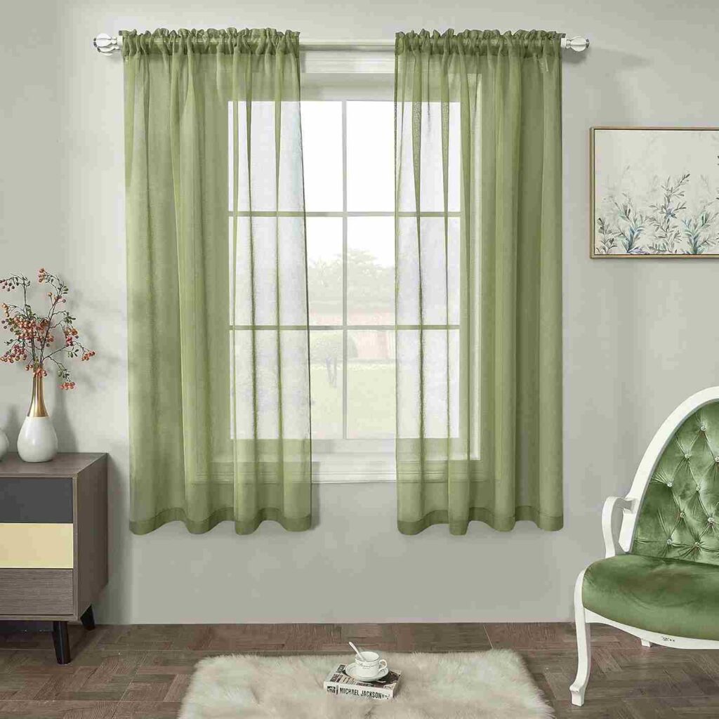 A grey wall against sheer sage curtains