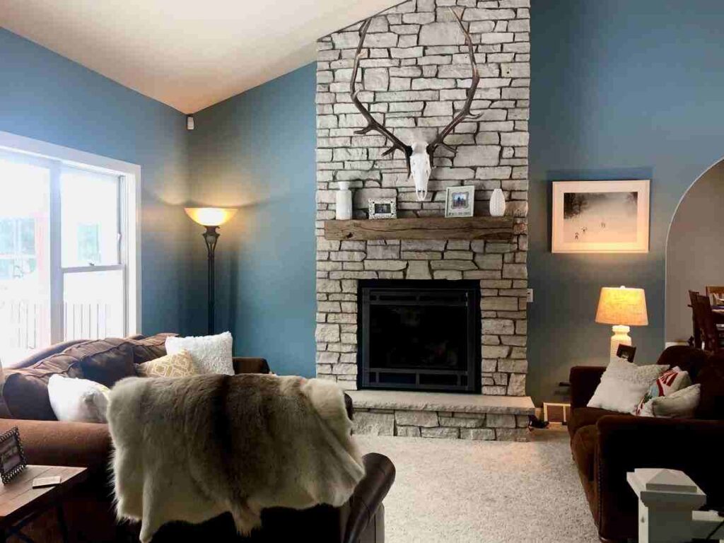 A brown living room with stone fireplace and white windows