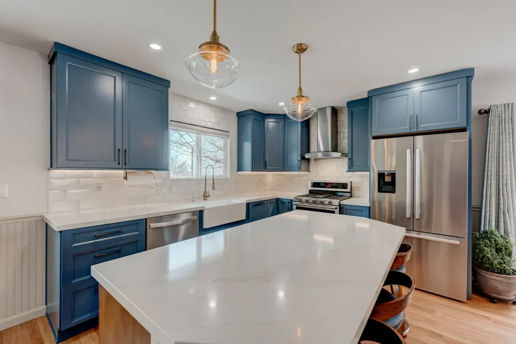 A blue kitchen and white counter top on blue cabinets and wooden floor