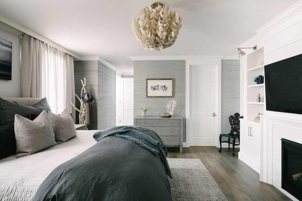 A bedroom with grey accents and wooden floor and rug on it 