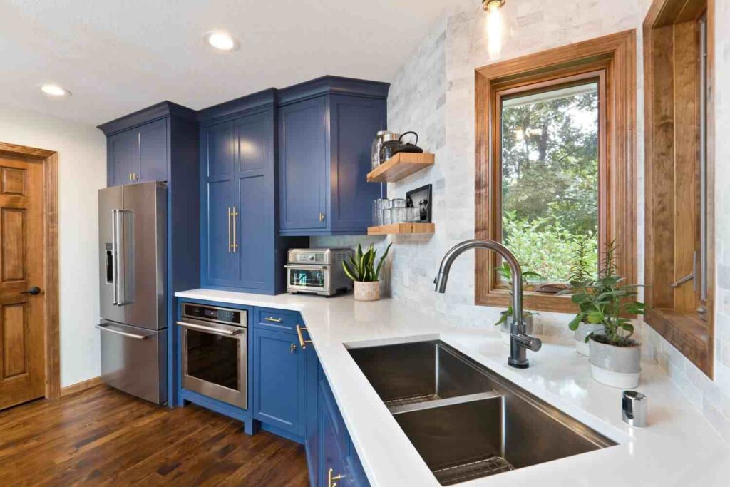 A blue cabinets and white countertop and sink and wooden floor