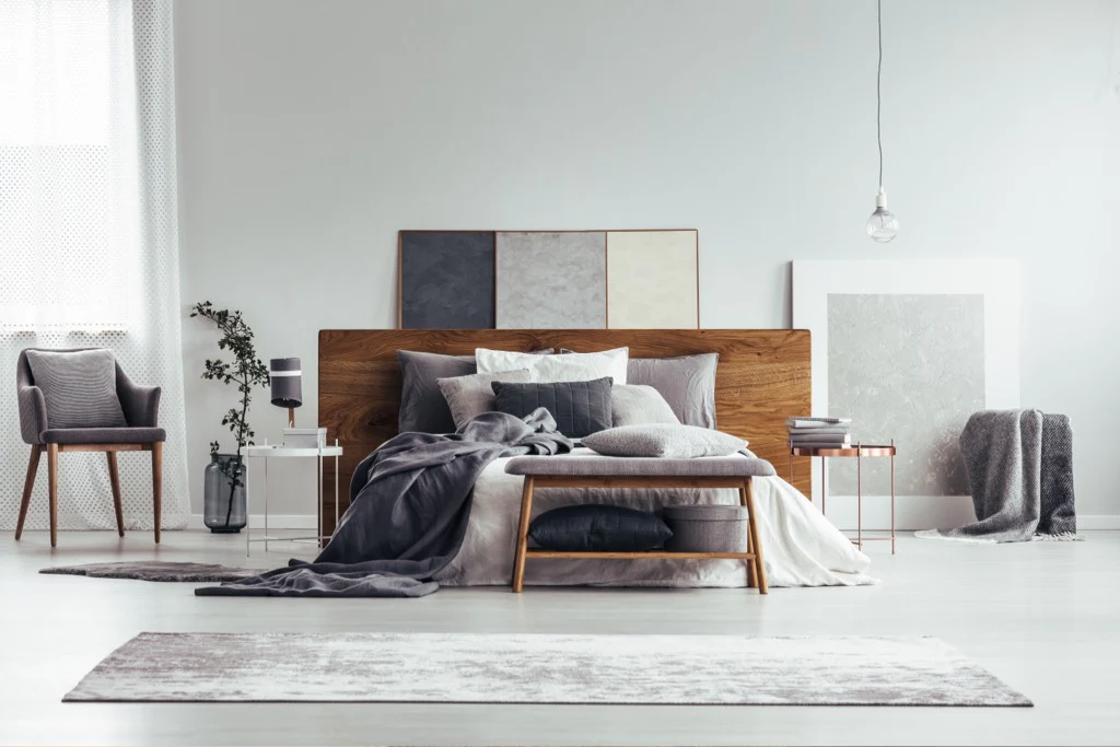White wall and wooden panel behind the bed and white bedding with throw pillows