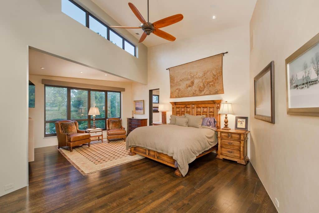 Wooden flooring and bed frame with beige wall and a tapestry on wall