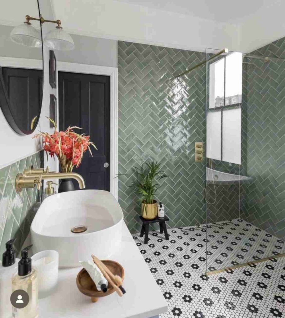 A green bathroom with herringbone tiles in the shower area