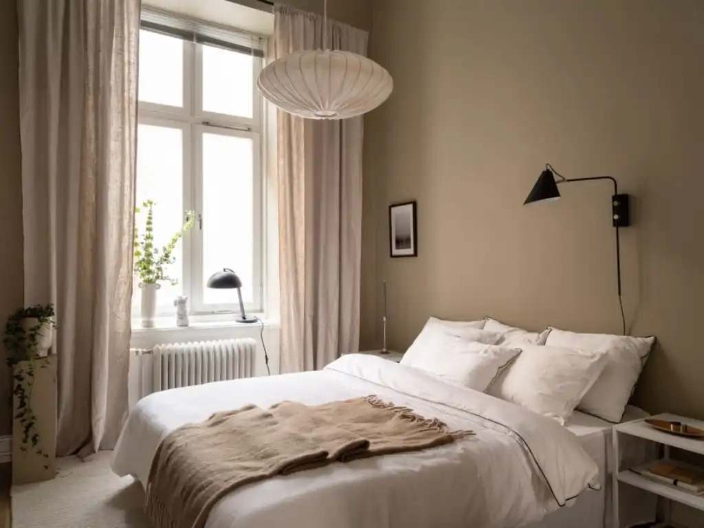 A bedroom with sheer curtains and black fixture 