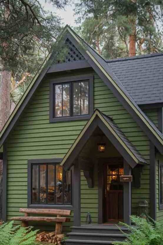 A green house with black windows and warm lights 