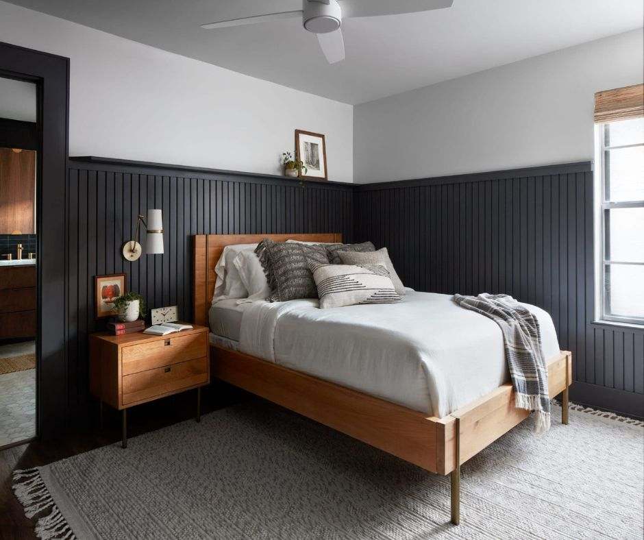 Black wood panels on wall and a wooden light brown bed frame