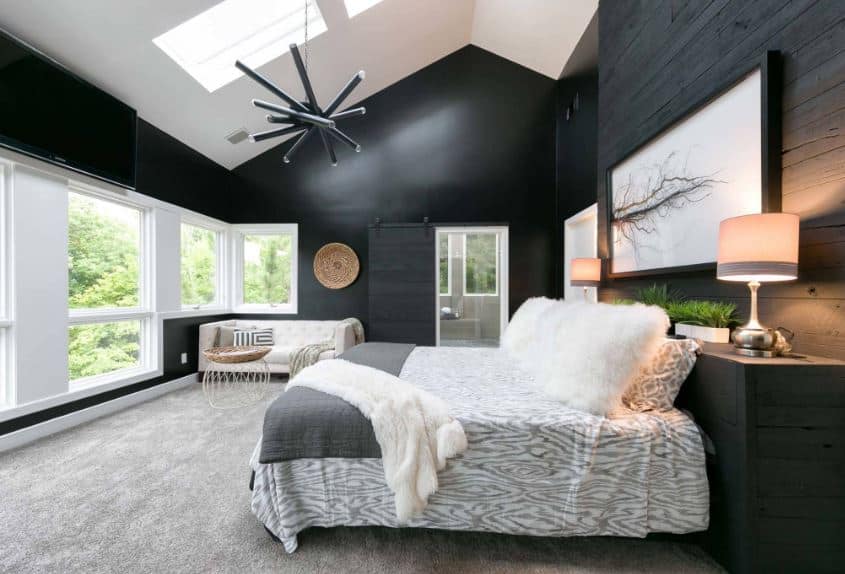 A black walls with white celling and bed and side lamp on the table