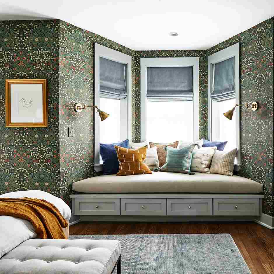 A bedroom with cozy beach with pillow and white framed windows