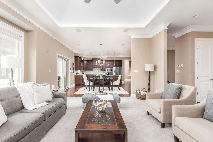 A beige living room with white trim and grey and beige sofa with wooden table 
