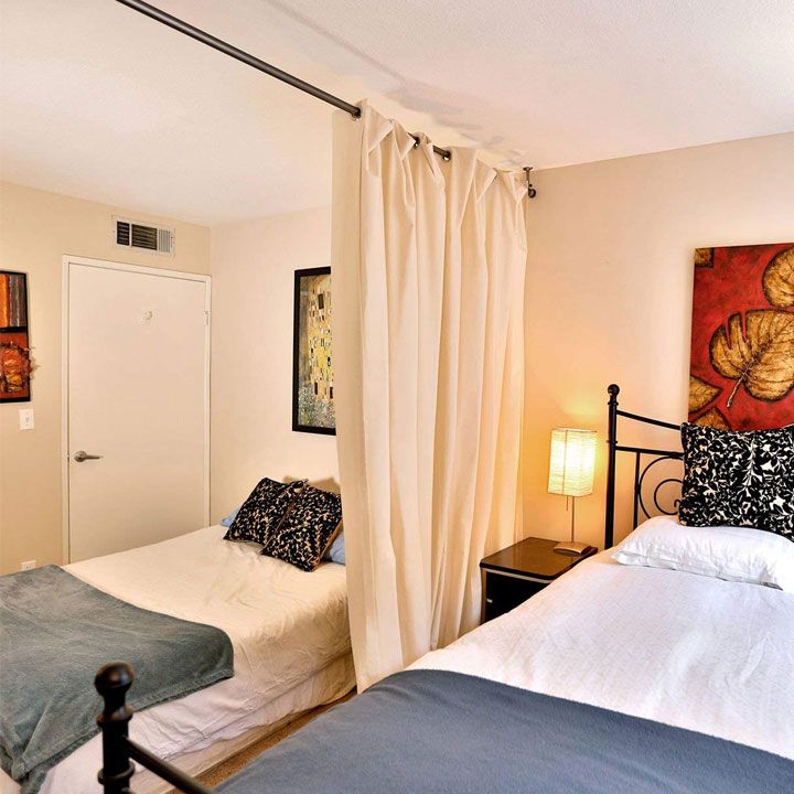 A curtains divider for bed and black framed frames and lamp on the side table  