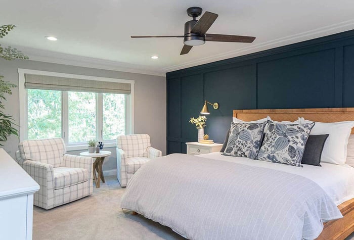 A dark blue room with grey accents with bed and sofa