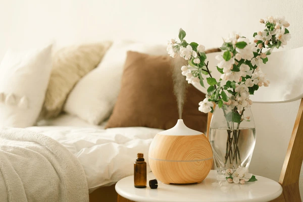 A bedroom with essential oil diffuser on side table and vase on it