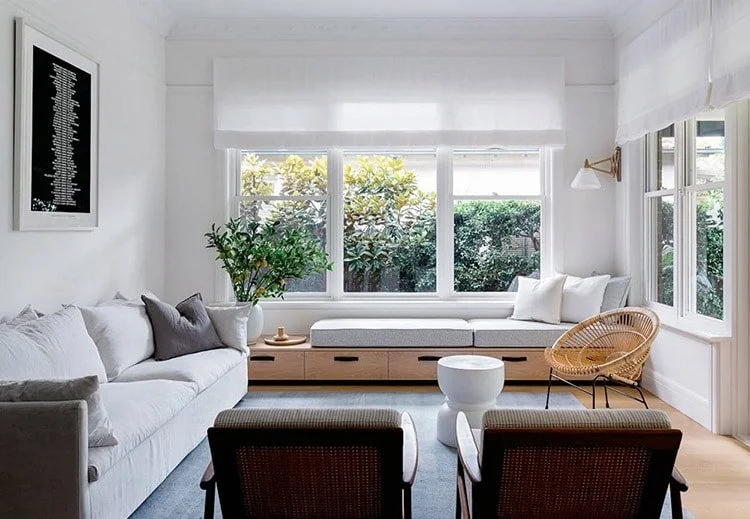 A small living room with extra bench and windows