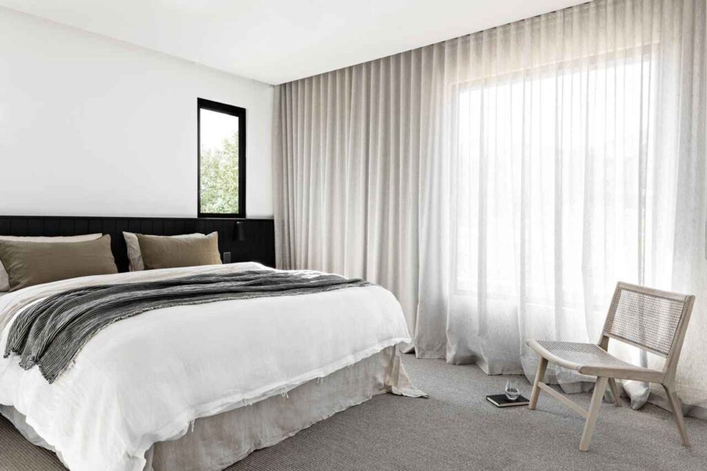 A bedroom with hang celling to floor drapes