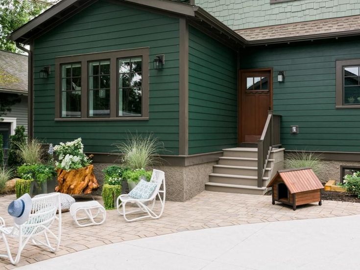 A forest green house with black trim and windows and wooden door 
