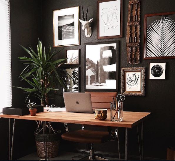A dark office with gallery wall and wooden table 