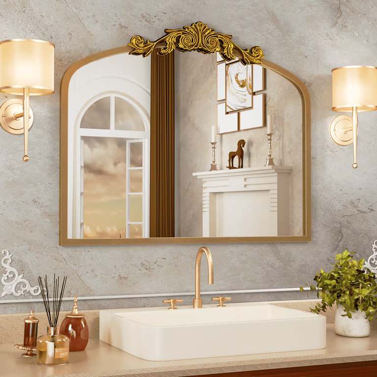 A bathroom with gold framed mirror on the wall 